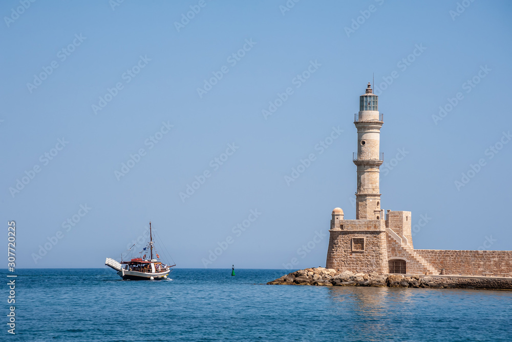 Fishing boat at sea against the background of a lighthouse tower