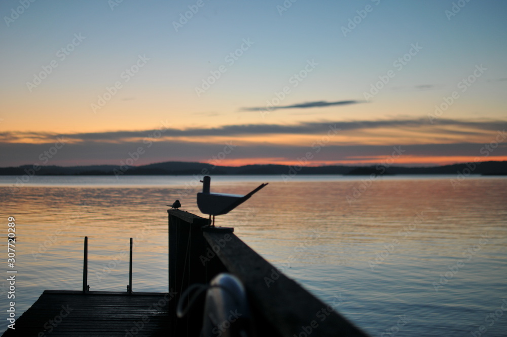 A wooden bird perched atop a fence near water