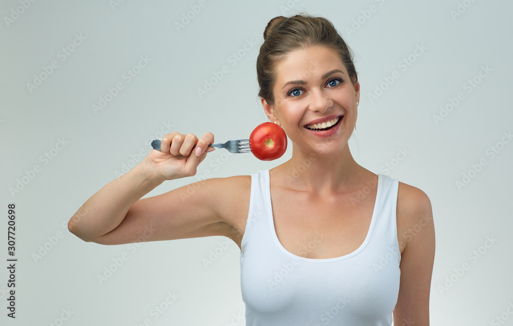 Smiling woman holding tomato on fork. Smiling woman holding tomato on fork.