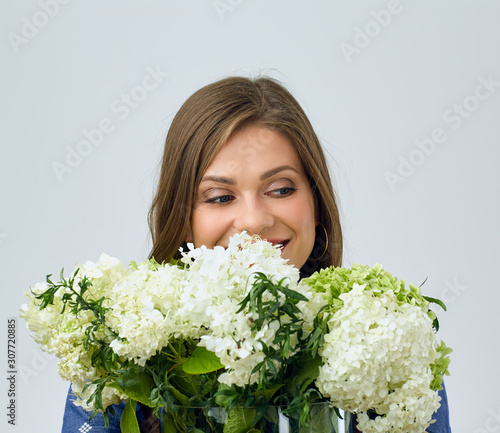portrait of woman holding white flowers in front of face and looking away.
