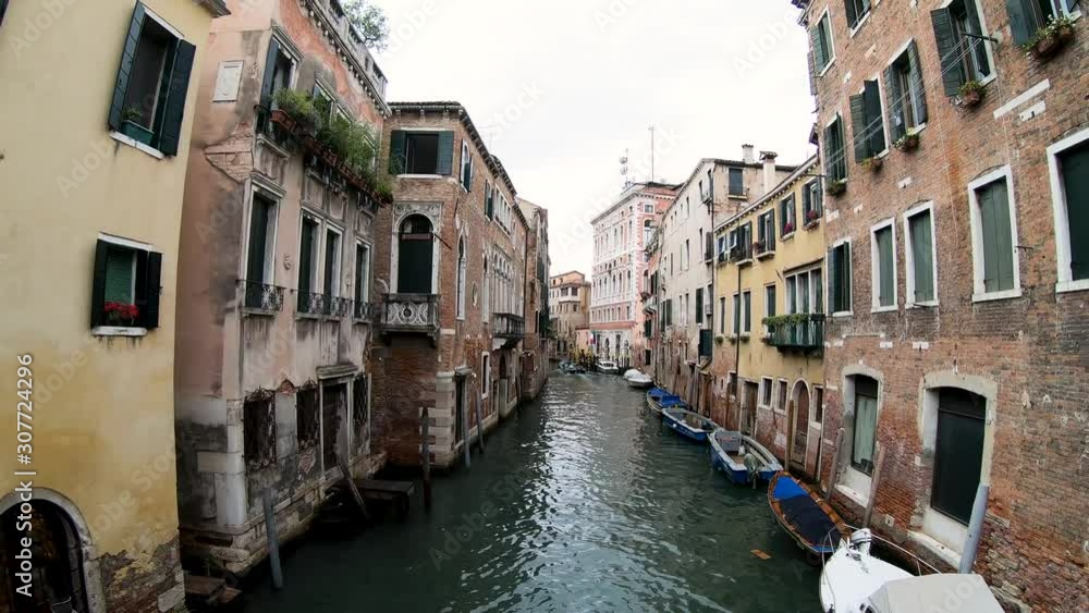 man sailing on gondola through water channel near buildings in Venice, Italy