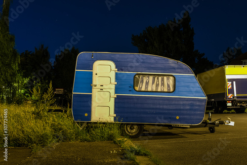 Fotografia Small caravan in a parking lot, A small blue caravan at night
