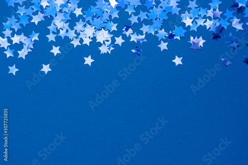 Blue abstract Christmas background or texture with stars confetti on blue background. Space for text.
