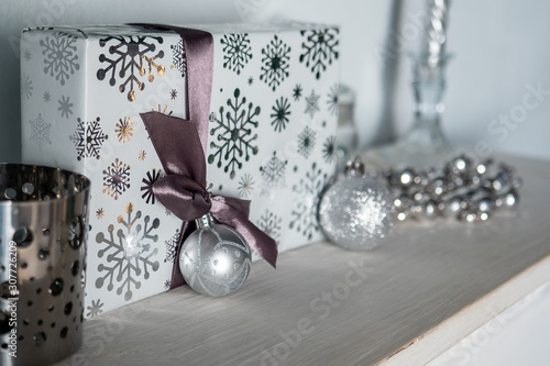 Christmas gift on the mantel. silver box and ball. brown ribbon. close up