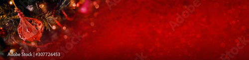 Red Christmas banner of tree decorations and a warm, red blurred festive background.