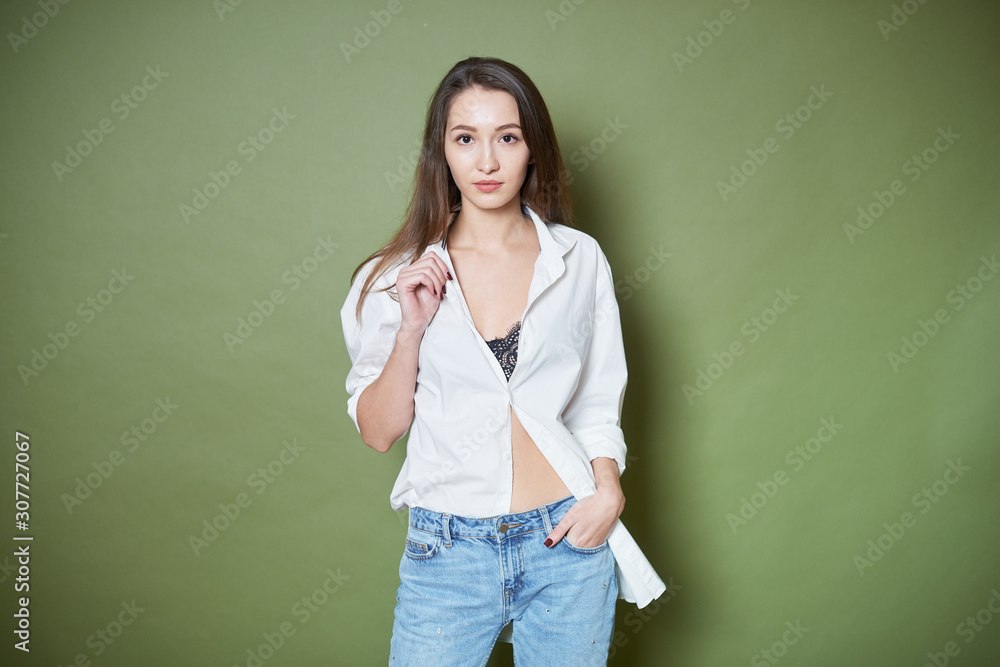 Attractive young woman posing in studio on green background in white shirt Attractive young woman posing in studio on green background in white shirt