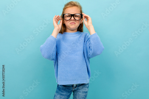 cute european girl squinting in glasses on a light blue background