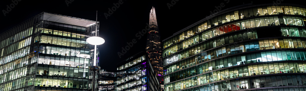 Modern offices in a large glass fronted building at night panoramic Modern offices in a large glass fronted building at night panoramic