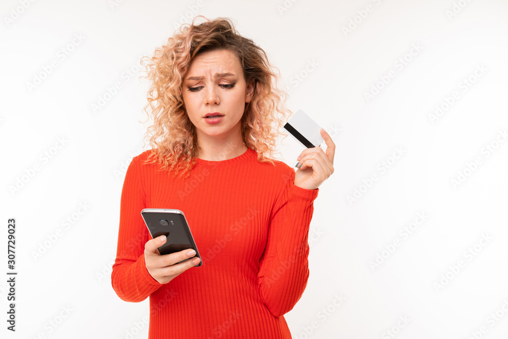 curly attractive girl with phone and credit card against white studio wall curly attractive girl with phone and credit card against white studio wall