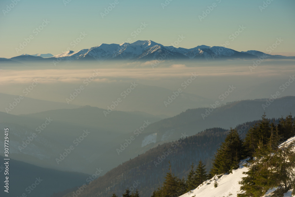 Traveling tourists on the snowy winter mountain ranges of the Ukrainian Carpathians with beautiful views of the evening peaks.
