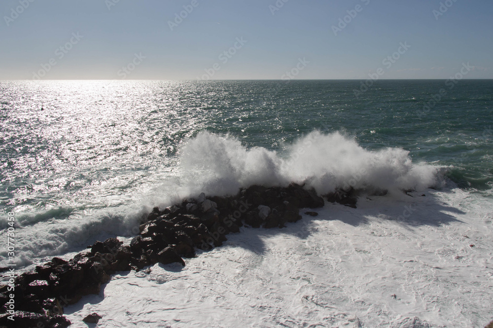 Seascape with horizon line over sea and wave is crashing stones.