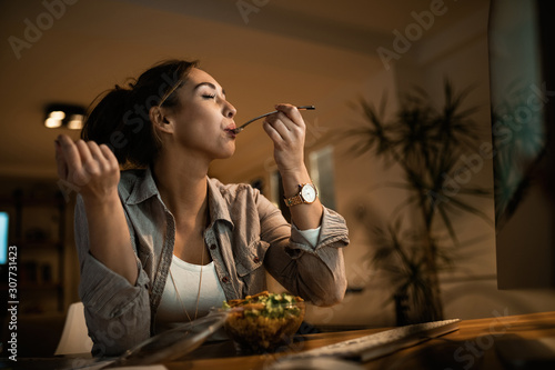 Fototapeta Below view of woman with eyes closed enjoying in a taste of healthy salad