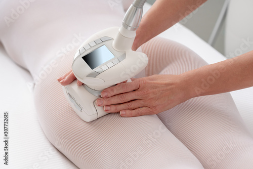 Woman in special white suit getting anti cellulite massage in spa salon. LPG and body contouring treatment photo