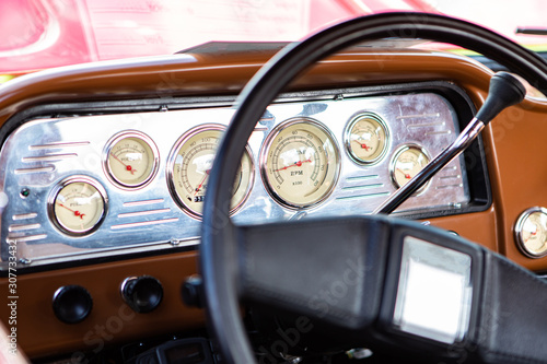 classic antique car black steering wheel and brown Dashboard close up, simple old style cars interior, Speed Counter, tachometer and other Counters © Valmedia