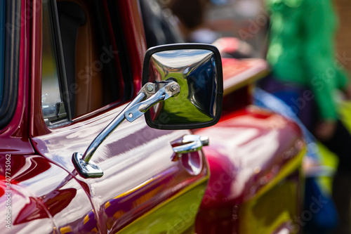 фотографія classic antique American red pickup car side chrome mirror close up view, people