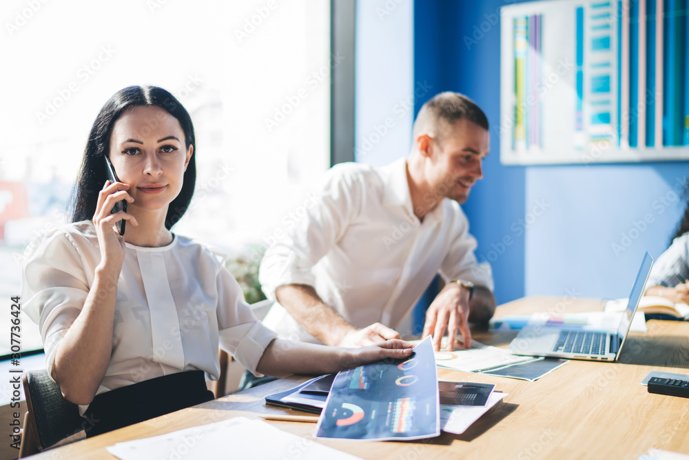Obraz premium Confident elegant businesswoman phoning while sitting at table in office