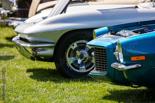 Old Classic American white and blue fast cars front  side view on the grass during an outdoor sunny day show  with chrome body parts and open hood