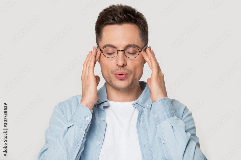 Young caucasian man in eyeglasses massaging temples. Young caucasian man in eyeglasses massaging temples.