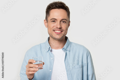 Smiling happy healthy young man holding glass of water.