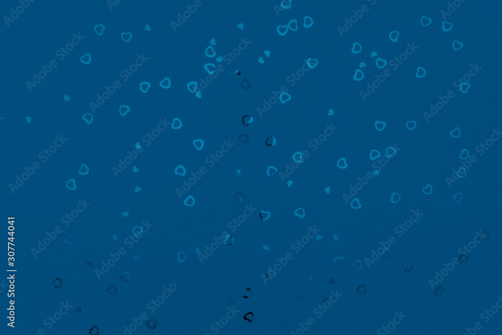 Classic blue abstract background. Festive concept. Color of the year 2020 concept. Blue confetti in shape of heart sparkling on blue backdrop Classic blue abstract background. Festive concept. Color of the year 2020 concept. Blue confetti in shape of heart sparkling on blue backdrop