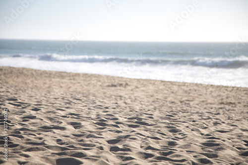 Sandy beach with an ocean shoreline in the blurry background