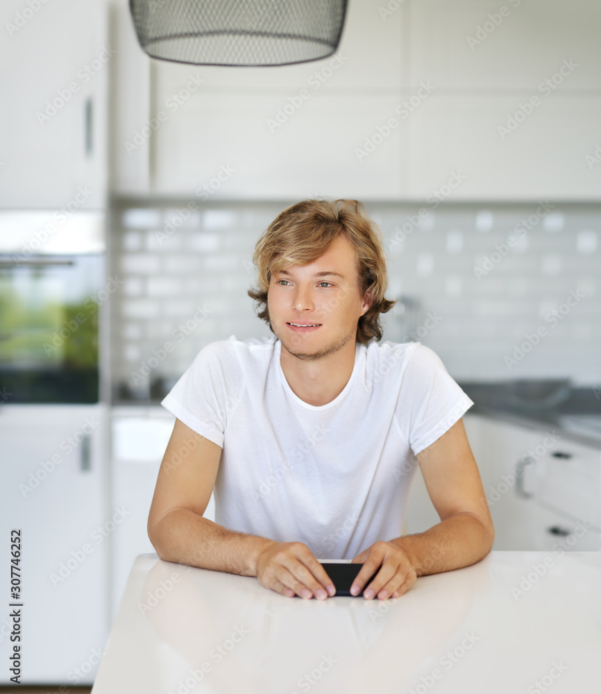 Teenage boy typing text message.Sitting in the kitchen.Using smart phone Teenage boy typing text message.Sitting in the kitchen.Using smart phone