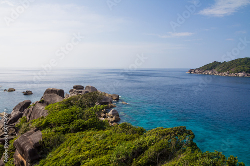 Beautiful tropical view of the sea with wild rocky islands covered with vegetation. Sunny day with blue sky. Transparent azure water, bottom of ocean is visible. Calm, relaxing, warm weather.
