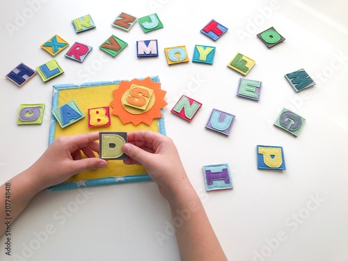 Learning the alphabet with a child. Hands hold letters. Learn by playing.