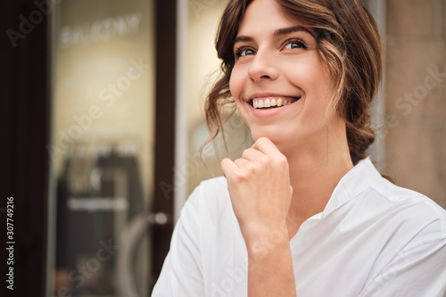 Portrait of young pretty cheerful woman happily looking away in modern workshop