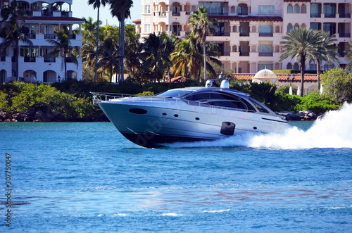 High-end cabin cruiser racing passed luxury island condominiums on its way to open ocean/ © Wimbledon