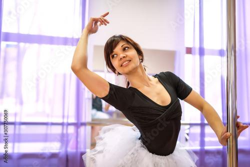 Woman in black jumpsuit and white tutu making ballet class near ballet machine