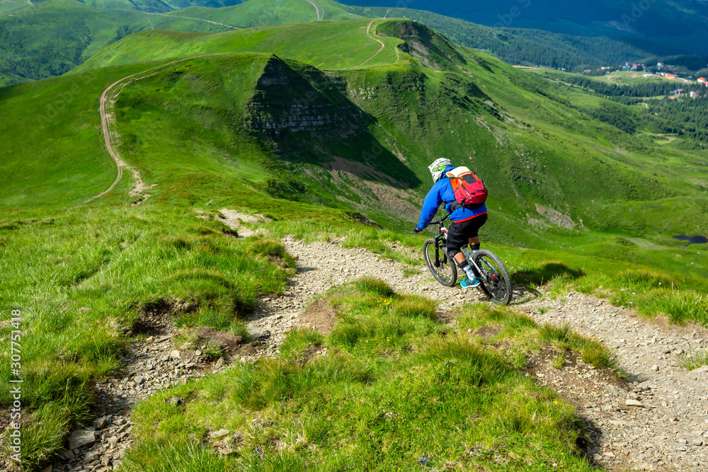 Enduro Cyclist in bright sportswear is riding down the hill.