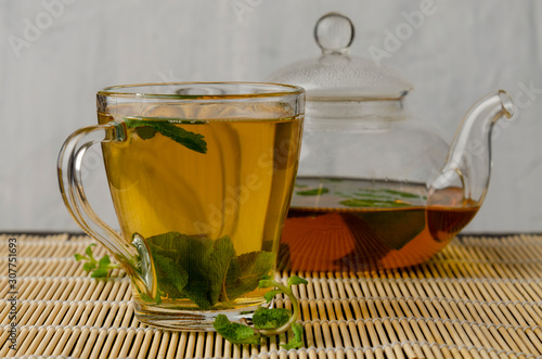 Cup and teapot of herbal tea with fresh mint on wooden