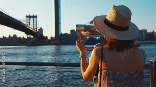 Young tourist looking through binoculars at the view point