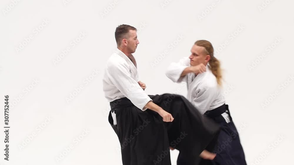Two guys in kimono demonstrating aikido techniques, isolated on white. Close up. Slow motion. Two guys in kimono demonstrating aikido techniques, isolated on white. Close up. Slow motion.