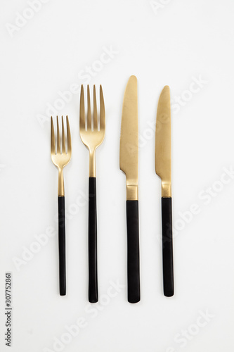 Black golden cutlery view from above on a white background. Top view..Knife and fork for a festive table for a wedding, birthday or party.