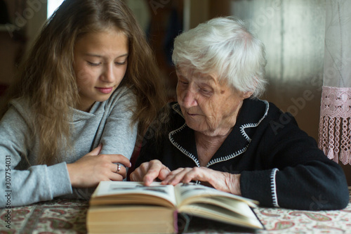 Little girl with her grandmother reading a book together.