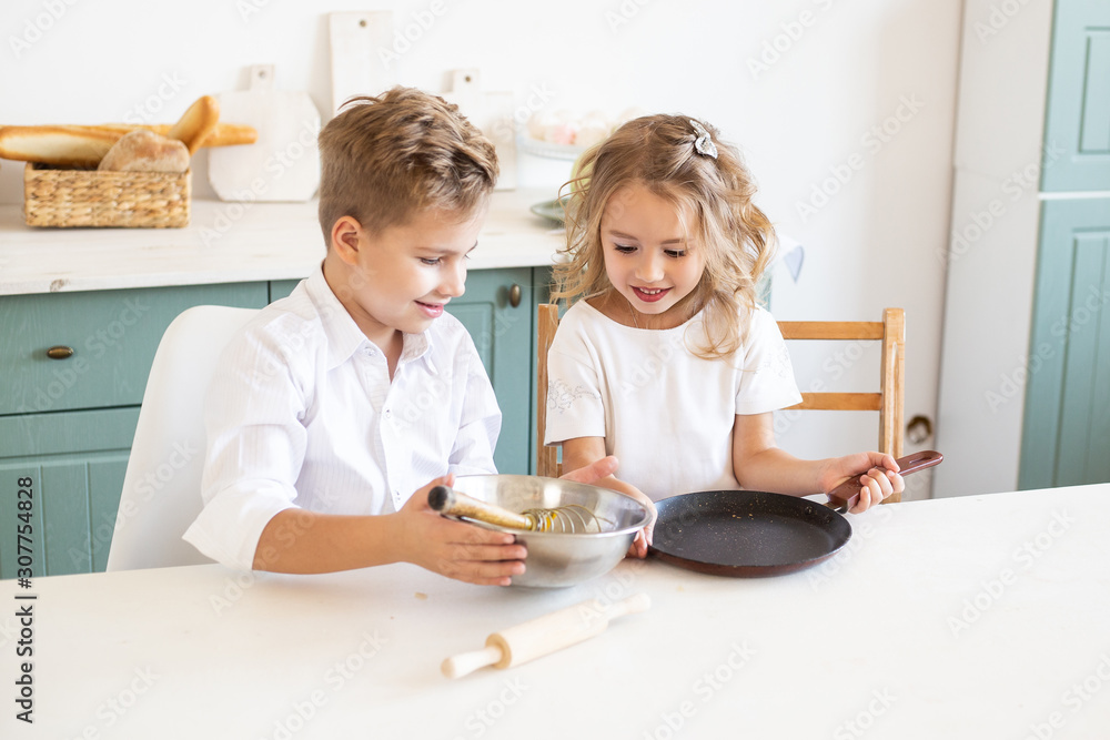 cute children cook pancakes in the kitchen at home