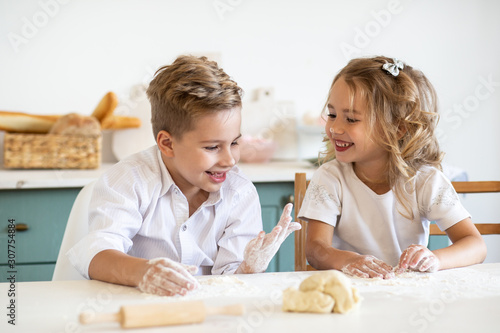Young children playing while cooking cookies together in kitchen