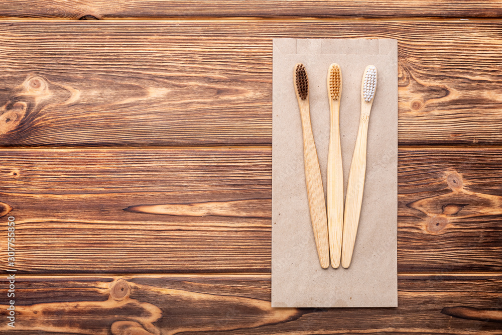Bamboo toothbrushes on wooden background. Flat lay with copy space. Natural bath products. Biodegradable natural bamboo toothbrush. Eco friendly, Zero waste, Dental care Plastic free concept