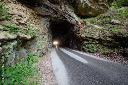 Dangerous Driving. Headlights of car exiting one lane tunnel on a narrow wet mountain road in Kentucky.