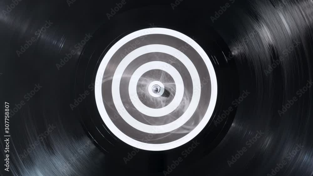 The vinyl record on DJ turntable record player close up. Black vinyl background with a black and white screen in center. The rotating plate and stylus with the needle close-up. Loop. Macro. View above The vinyl record on DJ turntable record player close up. Black vinyl background with a black and white screen in center. The rotating plate and stylus with the needle close-up. Loop. Macro. View above