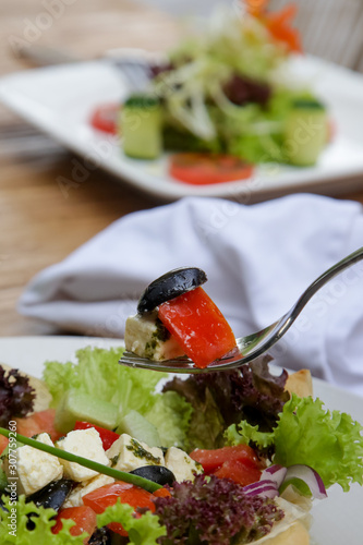 Classic Greek salad with feta cheese, tomato, cucumber, onion and olives erved on the restaurant table photo