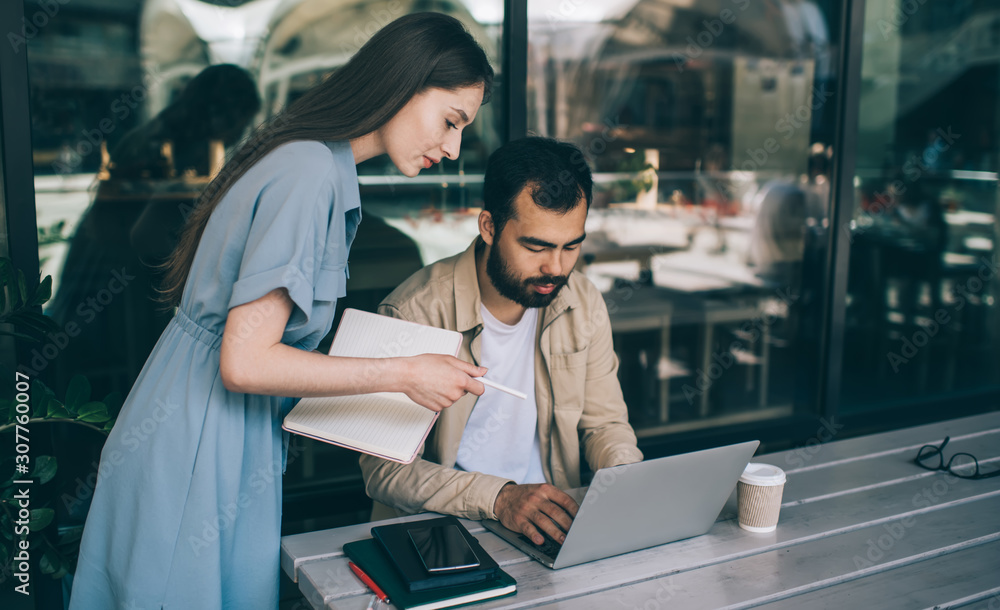 Obraz premium Young woman helping colleague with project