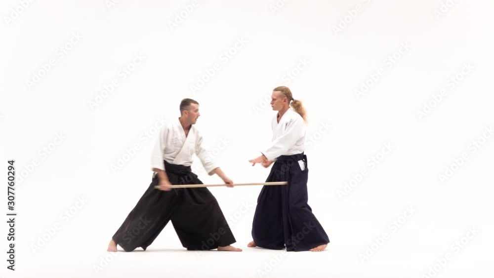 Two athletes performing aikido using bokken. Isolated, white. Slow motion. Two athletes performing aikido using bokken. Isolated, white. Slow motion.