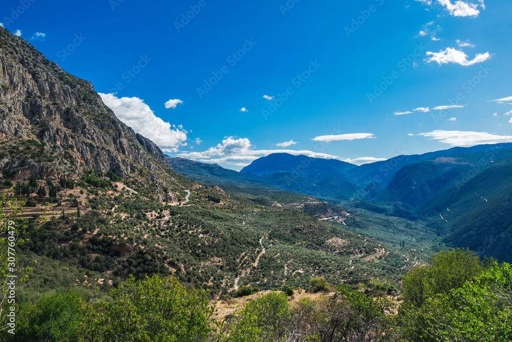 Scenic landscape with picturesque mountains, cloudy sky and coniferous forest on the Hillside near Delphi, Greece