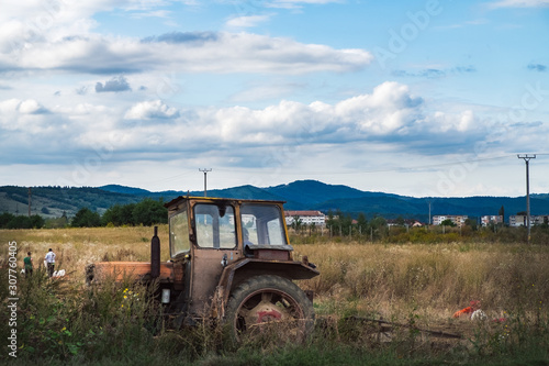 Farmers with an old and rusty tractor working his fields in autumn. Land farming and cultivation in Romania.
