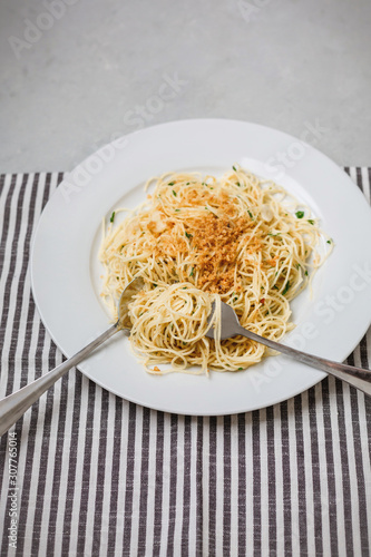 Vegan spaghetti on a white plate; gray and white napkin on gray countertop