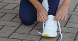 Young adult female tying shoe lace before a run