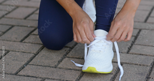 Young adult female tying shoe lace before a run